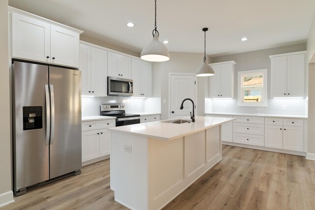 kitchen with tasteful backsplash, white cabinets, stainless steel appliances, light wood-style floors, and a sink