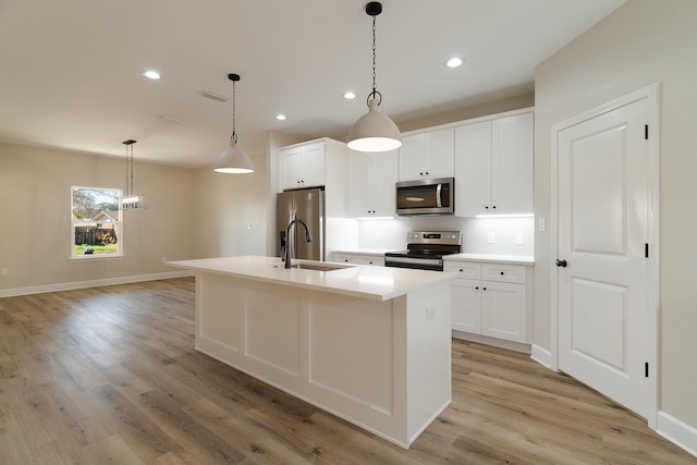 kitchen featuring visible vents, appliances with stainless steel finishes, a sink, an island with sink, and light wood-type flooring