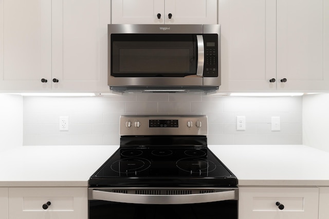 kitchen with white cabinetry, light countertops, decorative backsplash, electric range oven, and stainless steel microwave