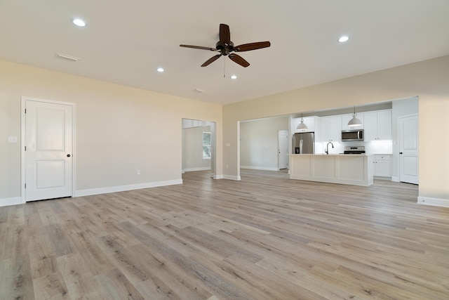 unfurnished living room featuring baseboards, ceiling fan, light wood finished floors, and recessed lighting