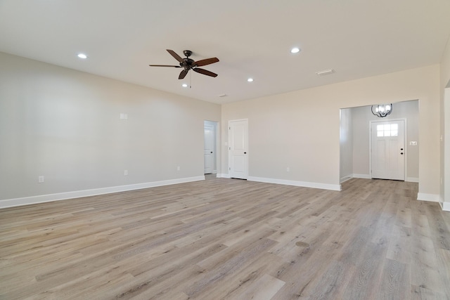 unfurnished living room featuring recessed lighting, light wood-style flooring, baseboards, and ceiling fan with notable chandelier