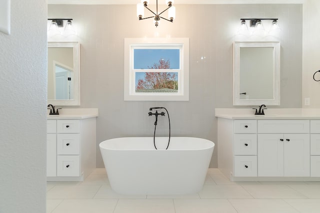 full bath with tile patterned flooring, a freestanding tub, a sink, two vanities, and tile walls