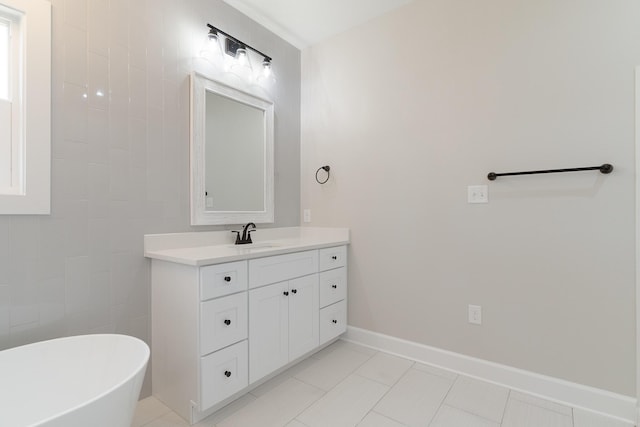 bathroom with tile patterned floors, a freestanding tub, vanity, and baseboards