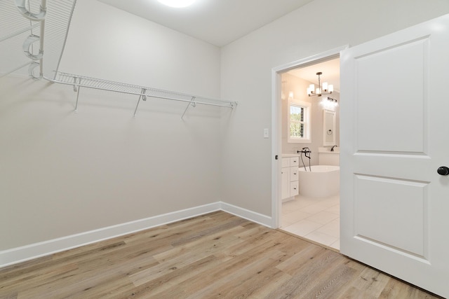 spacious closet featuring light wood-style flooring and a notable chandelier