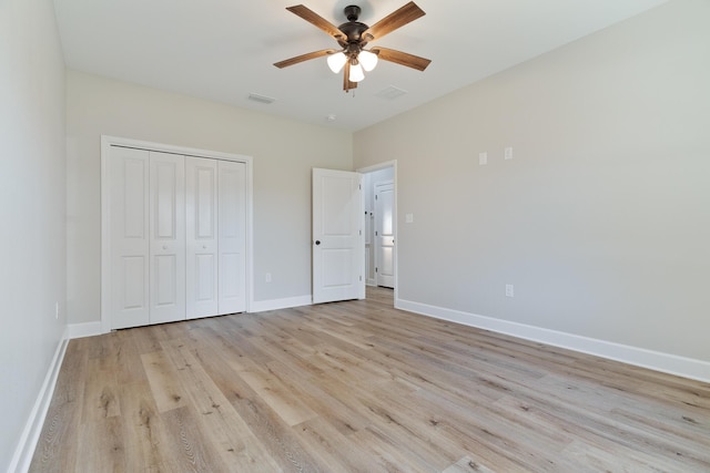 unfurnished bedroom featuring ceiling fan, light wood-style flooring, visible vents, baseboards, and a closet