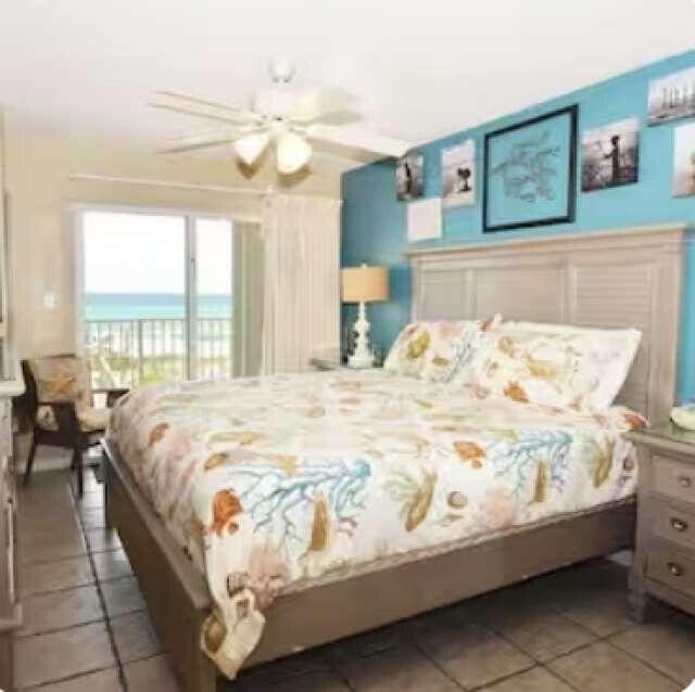 bedroom with a water view, access to outside, a view of the beach, and a ceiling fan