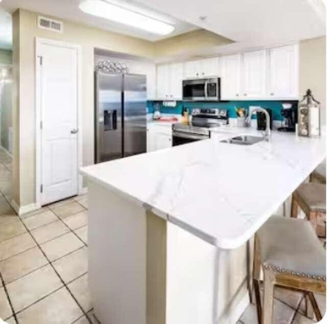 kitchen featuring visible vents, white cabinets, appliances with stainless steel finishes, a peninsula, and a sink