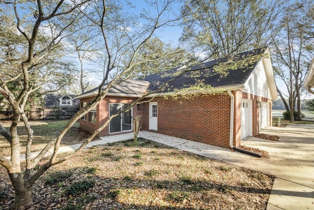 back of property featuring brick siding, driveway, and fence