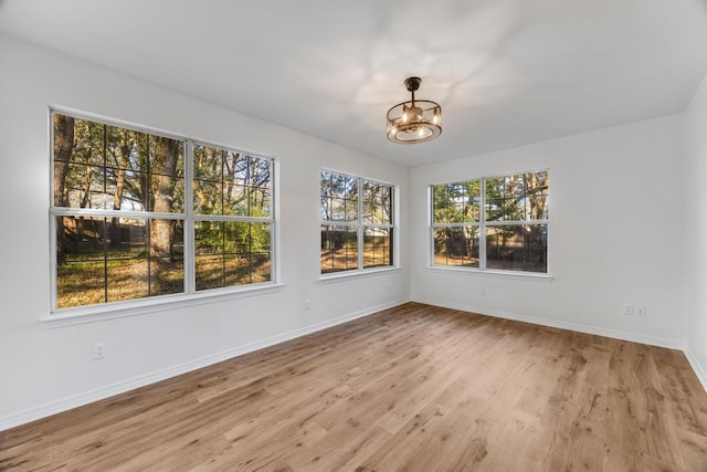 unfurnished dining area featuring wood finished floors, baseboards, and a chandelier