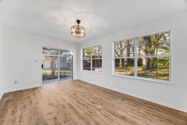 spare room featuring baseboards, a notable chandelier, and wood finished floors