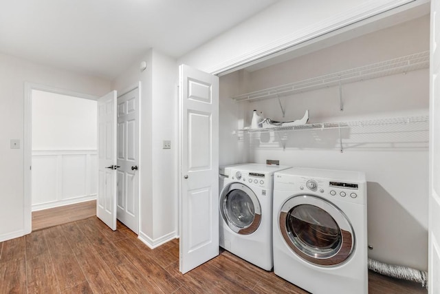 clothes washing area with baseboards, wood finished floors, laundry area, and washing machine and clothes dryer