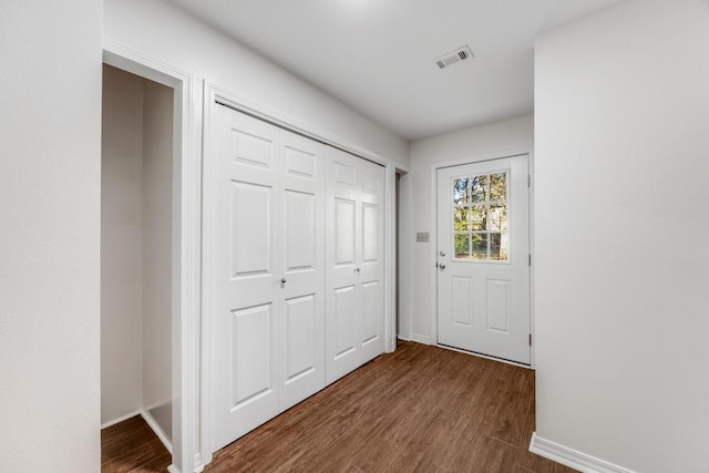 doorway to outside with dark wood finished floors, baseboards, and visible vents