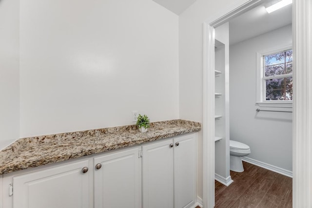 bathroom with toilet, wood finished floors, and baseboards