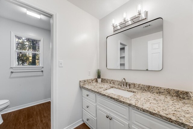 bathroom with visible vents, toilet, wood finished floors, baseboards, and vanity