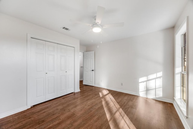 unfurnished bedroom featuring visible vents, wood finished floors, a closet, and baseboards