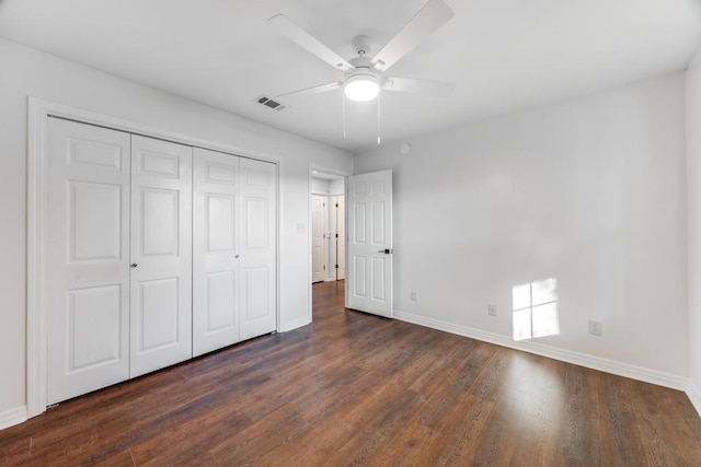 unfurnished bedroom featuring visible vents, baseboards, a closet, and dark wood-style floors