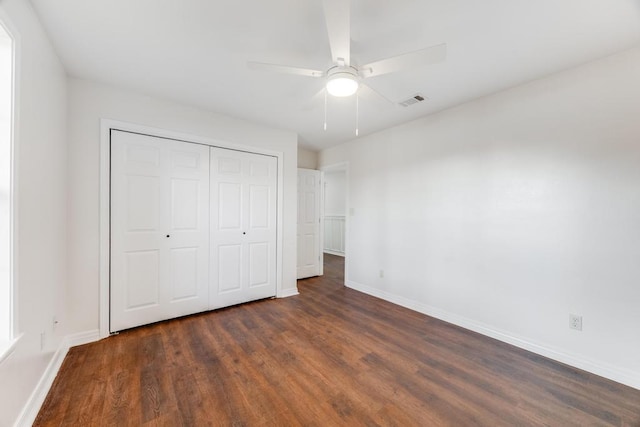 unfurnished bedroom with dark wood-type flooring, baseboards, visible vents, and a closet