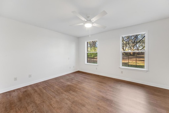 spare room featuring dark wood-style floors, a ceiling fan, and baseboards