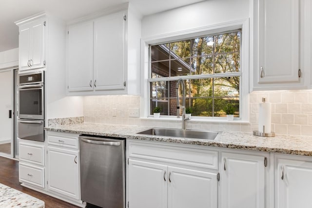 kitchen featuring backsplash, dark wood finished floors, appliances with stainless steel finishes, white cabinetry, and a sink