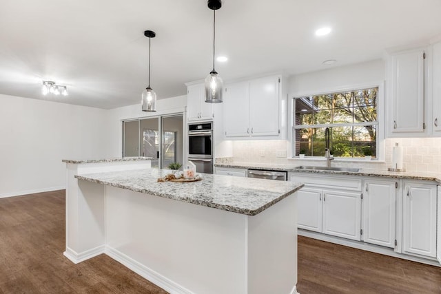 kitchen with dark wood-style flooring, stainless steel appliances, a sink, tasteful backsplash, and a center island