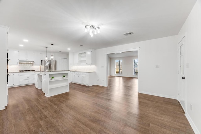 kitchen featuring open shelves, dark wood-style floors, visible vents, and stainless steel fridge