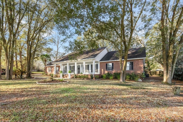 view of front of property featuring a front yard, a porch, and brick siding