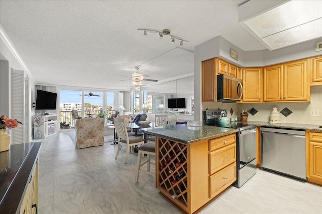 kitchen featuring a textured ceiling, open floor plan, appliances with stainless steel finishes, and ceiling fan