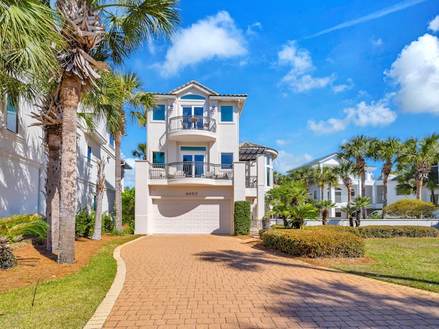 mediterranean / spanish-style house featuring a balcony, a garage, decorative driveway, and stucco siding