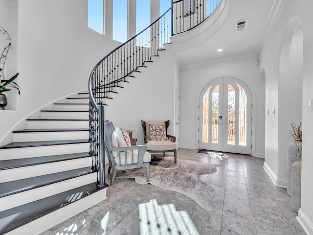 foyer entrance featuring arched walkways, french doors, a towering ceiling, ornamental molding, and baseboards