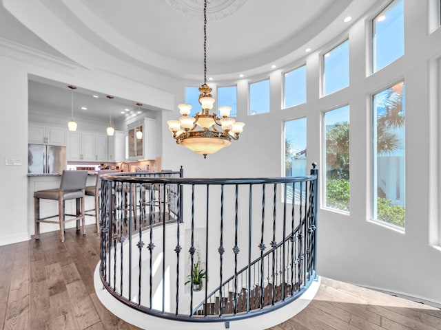 interior space featuring recessed lighting, an upstairs landing, ornamental molding, hardwood / wood-style floors, and an inviting chandelier