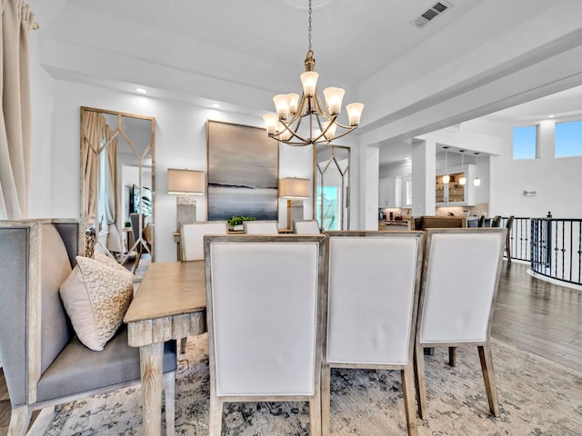 dining space with visible vents, a chandelier, and wood finished floors