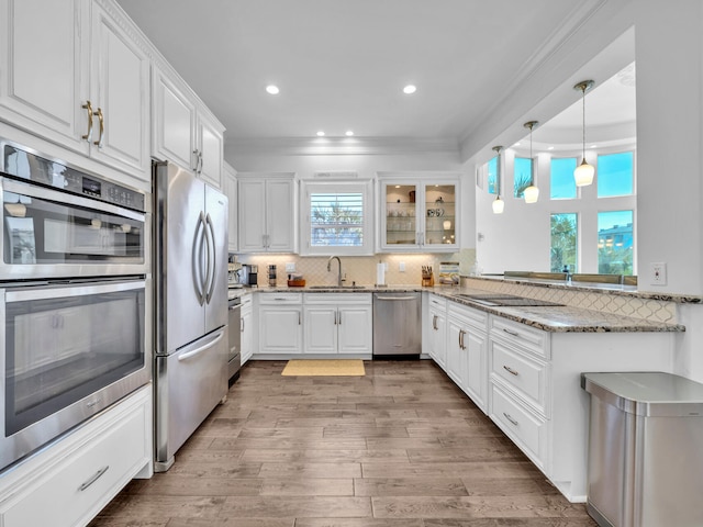 kitchen with white cabinets, decorative backsplash, stainless steel appliances, and a sink