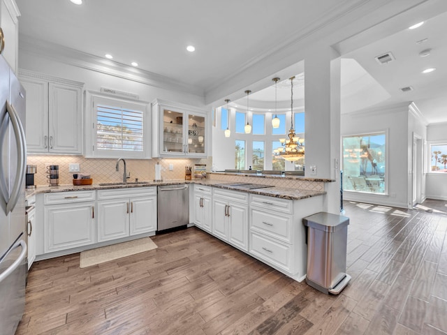 kitchen featuring visible vents, light wood-style flooring, ornamental molding, stainless steel appliances, and a sink