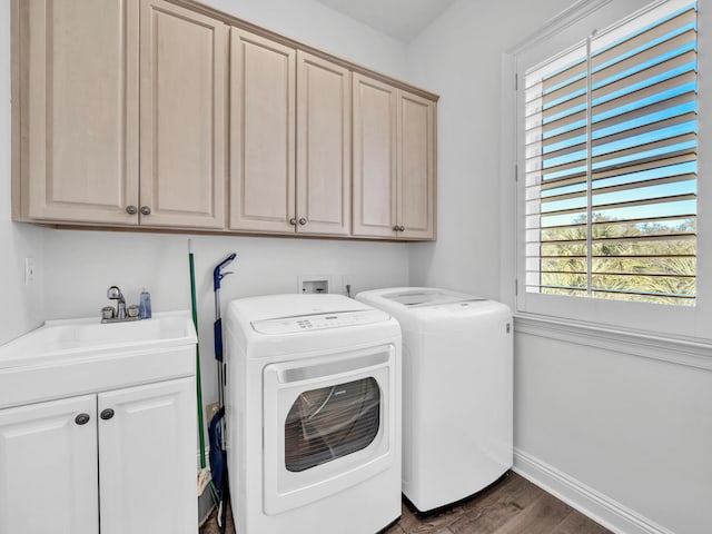 washroom with cabinet space, baseboards, dark wood-style flooring, washing machine and clothes dryer, and a sink