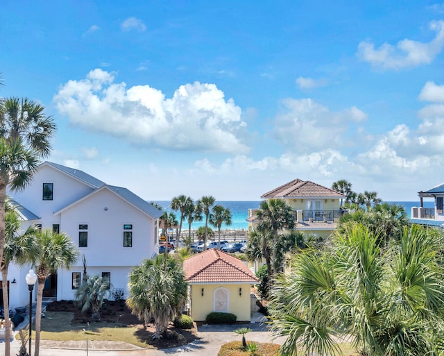 view of front facade featuring a water view, a tiled roof, and stucco siding