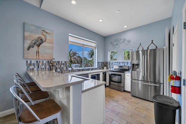 kitchen featuring a peninsula, light wood finished floors, appliances with stainless steel finishes, and light countertops