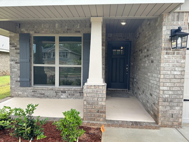 view of exterior entry with covered porch and brick siding