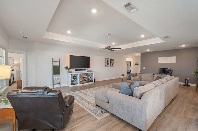 living area featuring recessed lighting, visible vents, baseboards, light wood finished floors, and a raised ceiling