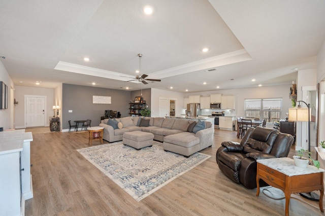 living room featuring light wood finished floors, a tray ceiling, and recessed lighting