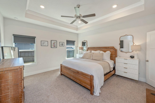 bedroom featuring a tray ceiling, light carpet, and baseboards