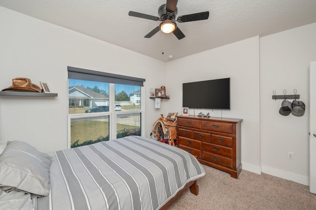 carpeted bedroom with a textured ceiling, ceiling fan, and baseboards