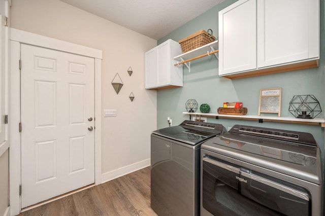 laundry room featuring cabinet space, baseboards, washer and clothes dryer, wood finished floors, and a textured ceiling