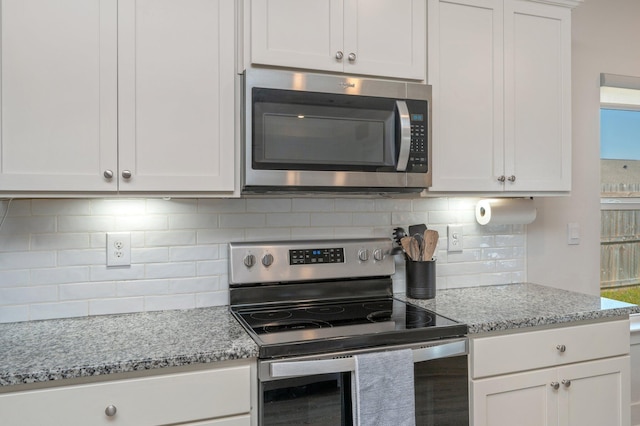 kitchen with appliances with stainless steel finishes, light stone countertops, white cabinets, and tasteful backsplash