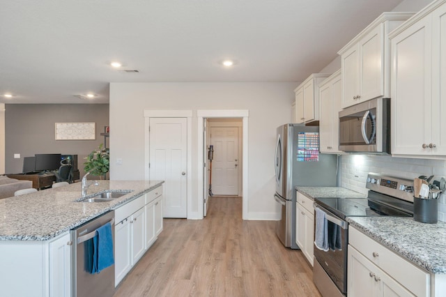 kitchen with light wood-type flooring, white cabinetry, stainless steel appliances, and a sink