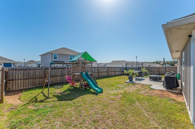 view of yard with a patio area, a fenced backyard, an outdoor fire pit, and a playground