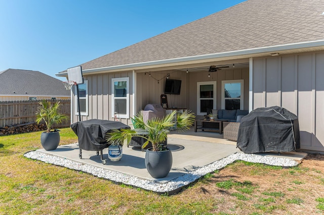 rear view of property with a yard, board and batten siding, a ceiling fan, a patio area, and fence