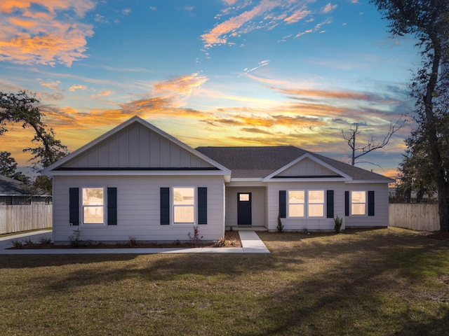 ranch-style house featuring board and batten siding, fence, and a lawn