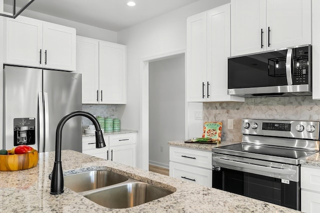 kitchen featuring decorative backsplash, white cabinetry, stainless steel appliances, and a sink