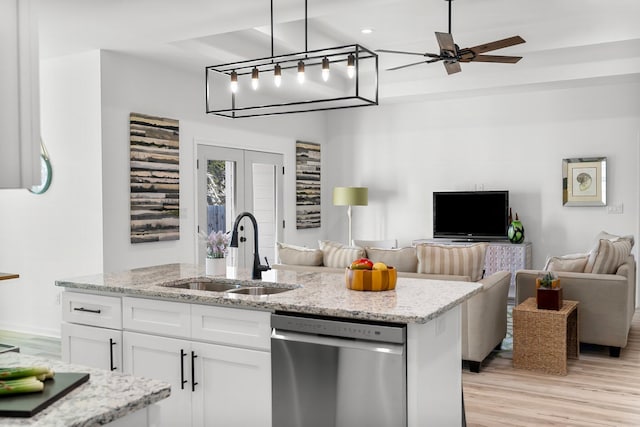 kitchen with french doors, stainless steel dishwasher, open floor plan, white cabinets, and a sink