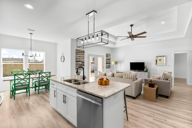 kitchen featuring a tray ceiling, french doors, light wood-style flooring, stainless steel dishwasher, and a sink